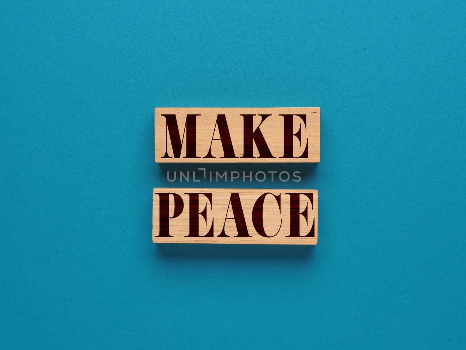 Wooden blocks with the inscription Make Peace on a blue background, freedom and peace concept