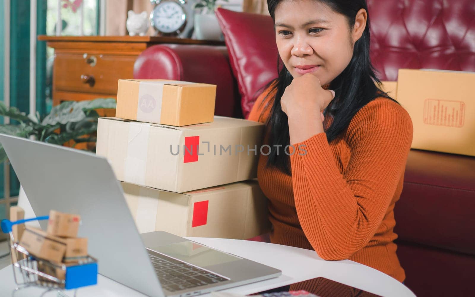 Asia women working business SME online at home her checking order from laptop for customer and online delivery for ready packing, Checking orders from customers with digital laptop, Small business.