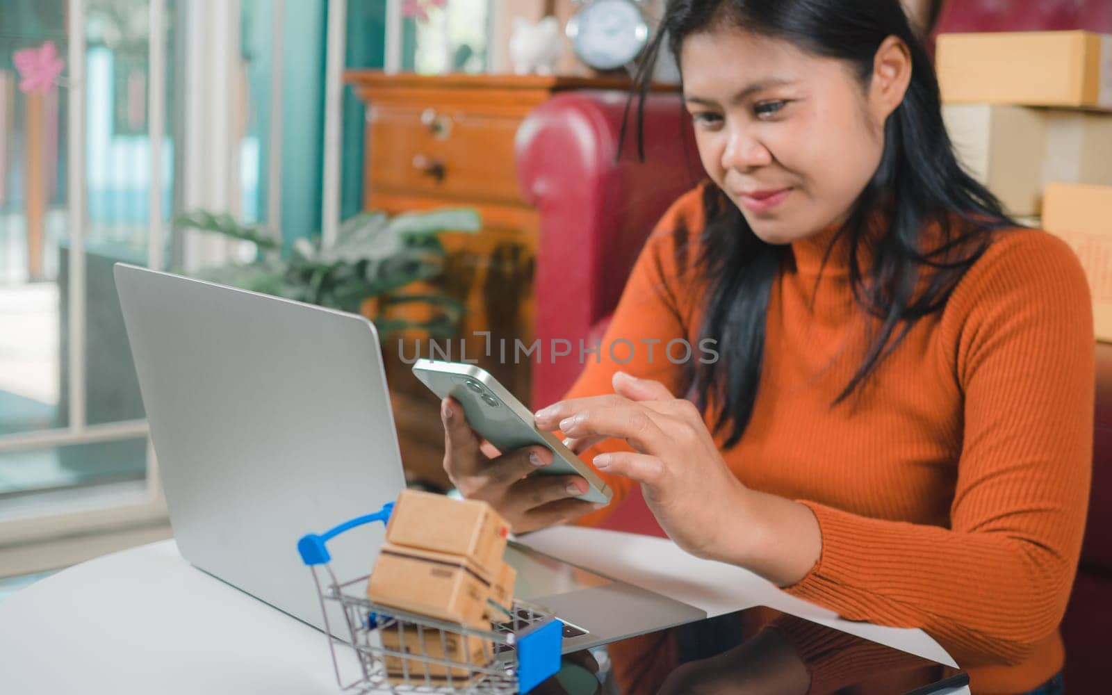 Asia women working business SME online at home her checking order from smartphone  for customer and online delivery for ready packing, Checking orders from customers with digital laptop.