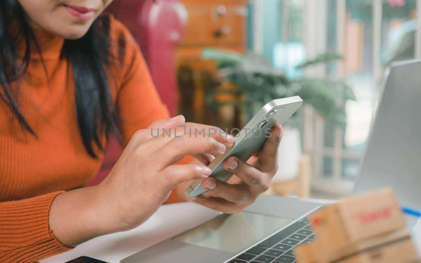 Asia women working business SME online at home her checking order from smartphone  for customer and online delivery for ready packing, Checking orders from customers with digital laptop.