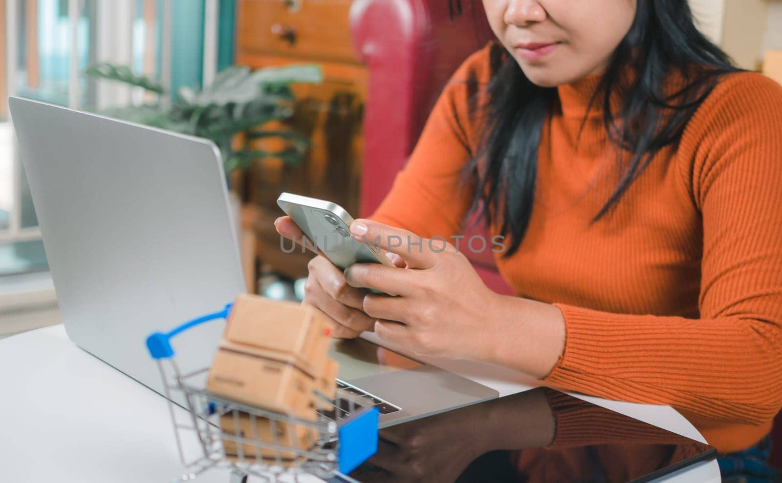 Asia women working business SME online at home her checking order from smartphone  for customer and online delivery for ready packing, Checking orders from customers with digital laptop.