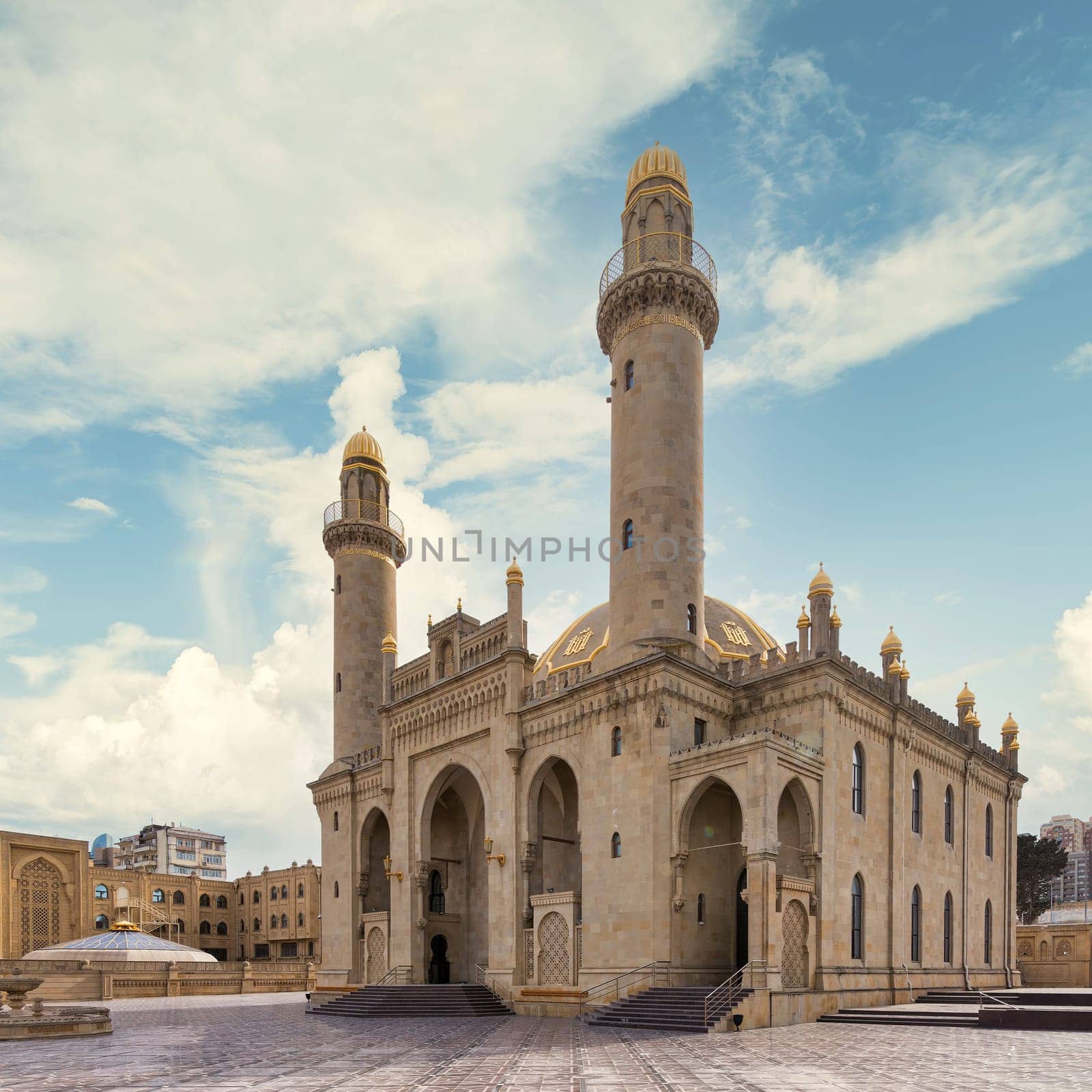 View of the majestic Taza Pir Mosque in Baku, Azerbaijan showcases intricate architecture with twin minarets against a peaceful blue clear sky
