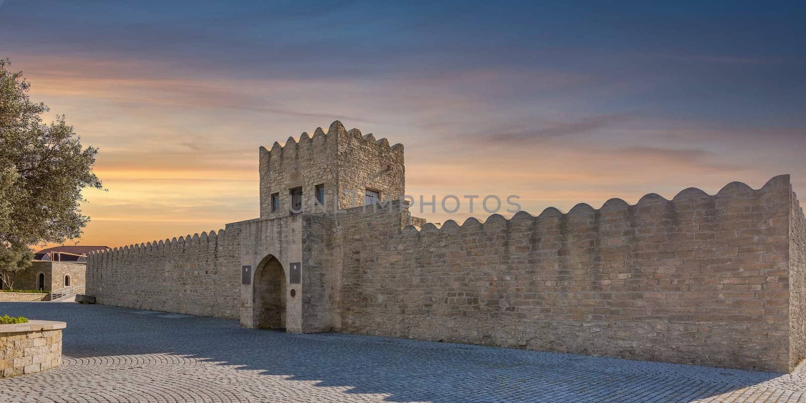 External facade of the Ateshgah Fire Temple in Baku, Azerbaijan, a historic Zoroastrian temple. The stone structure features a stone fence, an arched doorway and a tower with door and small windows