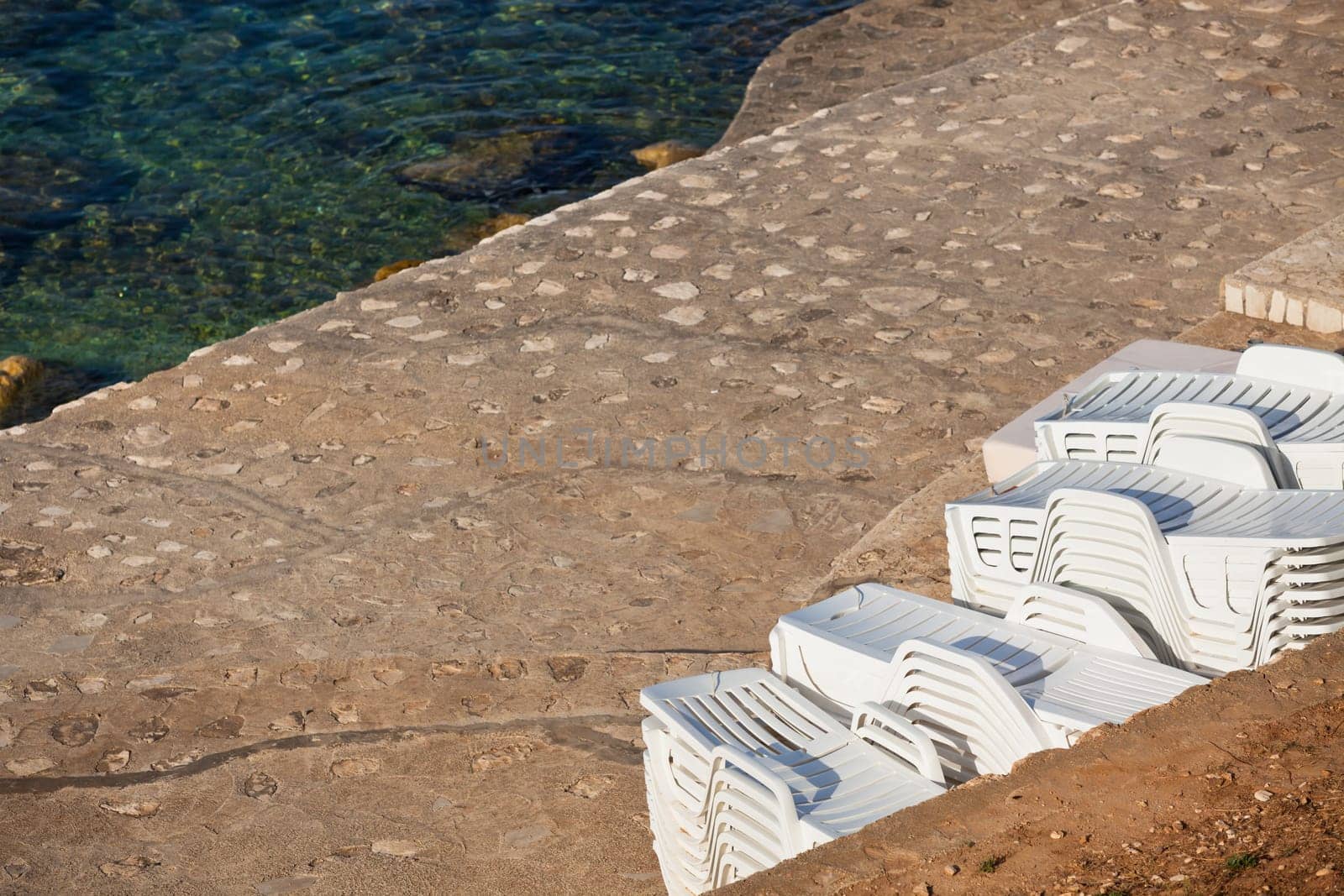 Plastic Poolside Chairs in a pile by the sea