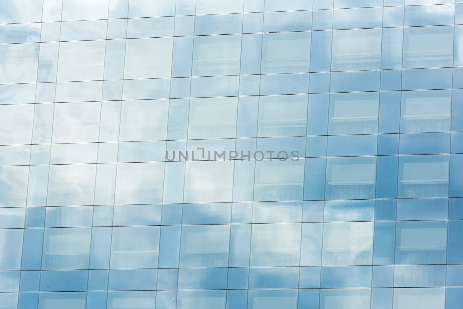 blue sky and clouds reflected in windows of modern office building