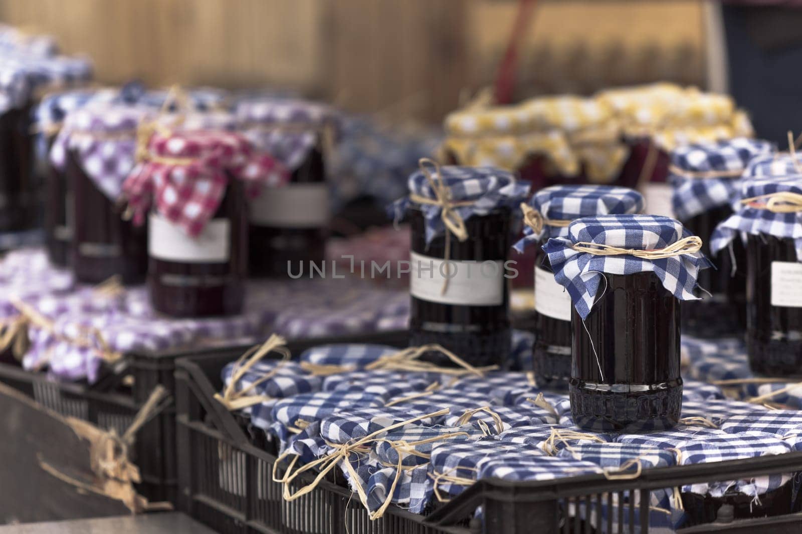 Many preserving jars with dark jam in a market. Horizontal filtered shot