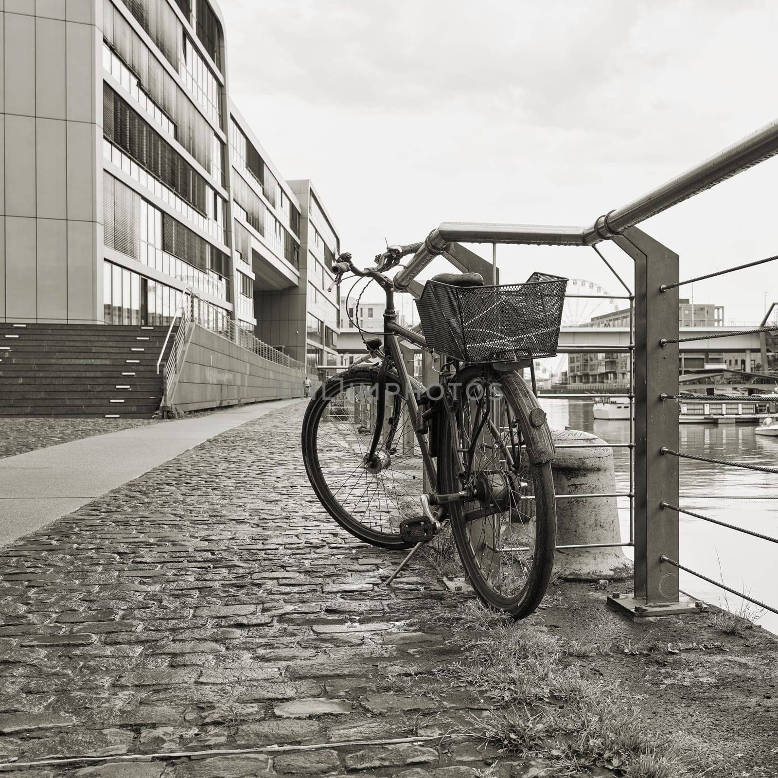 parked bicycle at a fence in the Rheinauhafen in the city of Cologne in Germany in black and white