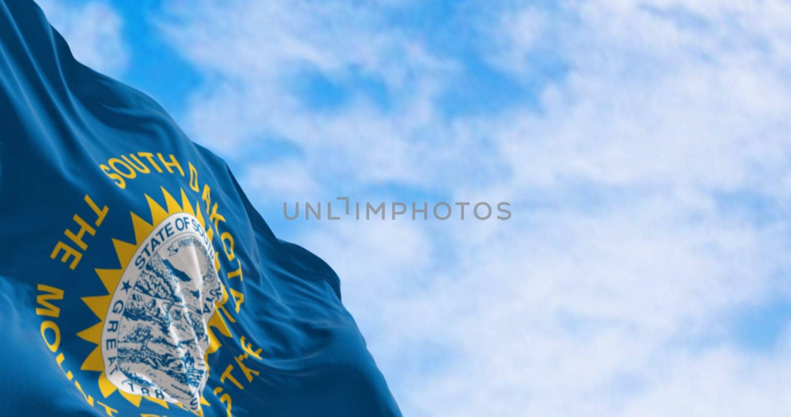 Close-up of the South Dakota flag waving in the wind. Sky blue field, the state seal, and inscriptions of South Dakota and The mount rushmore state. 3d illustration render. Fluttering fabric