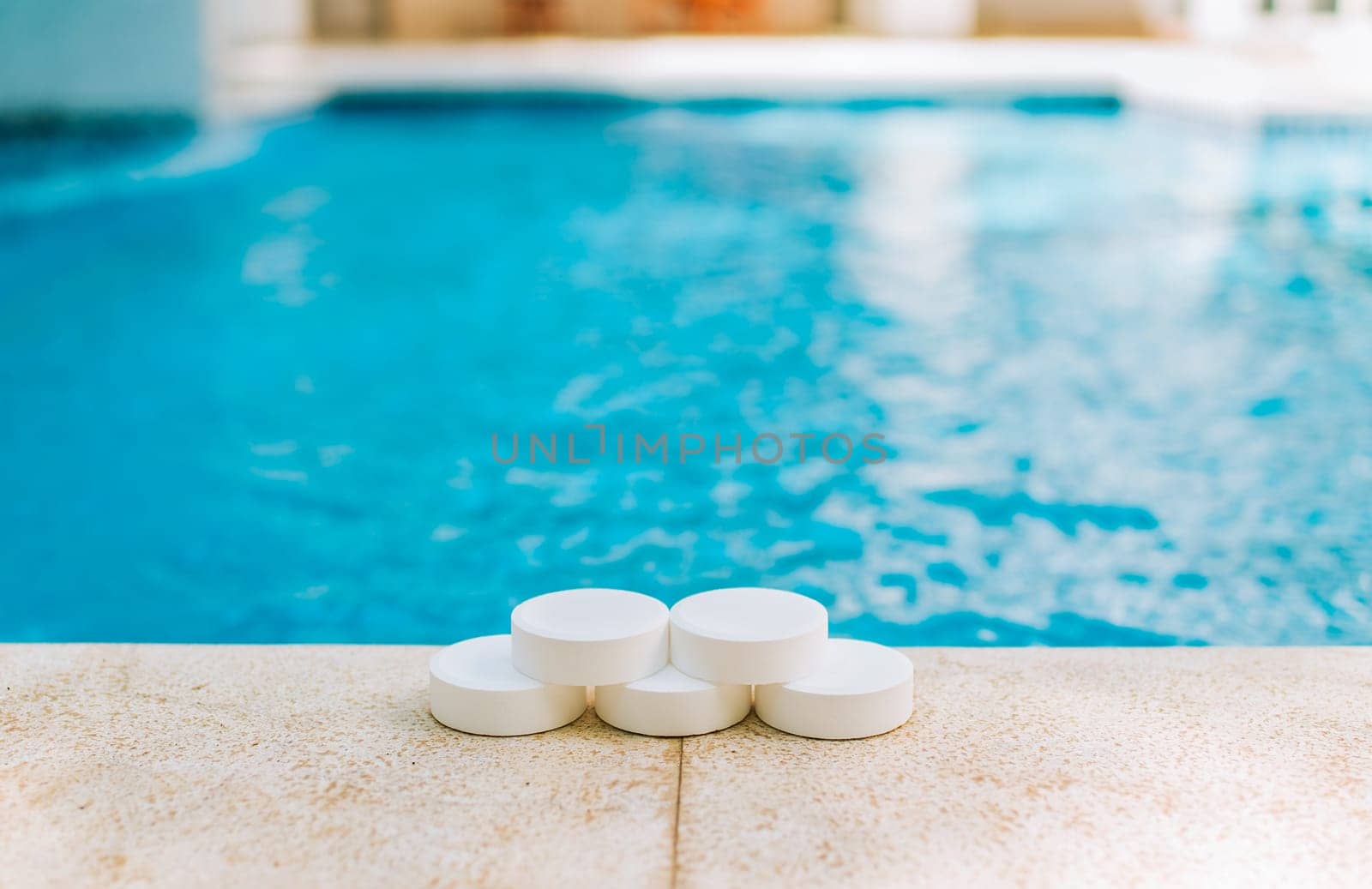 Close up of chlorine tablets on the edge of a swimming pool. Chlorine tablets for swimming pool cleaning