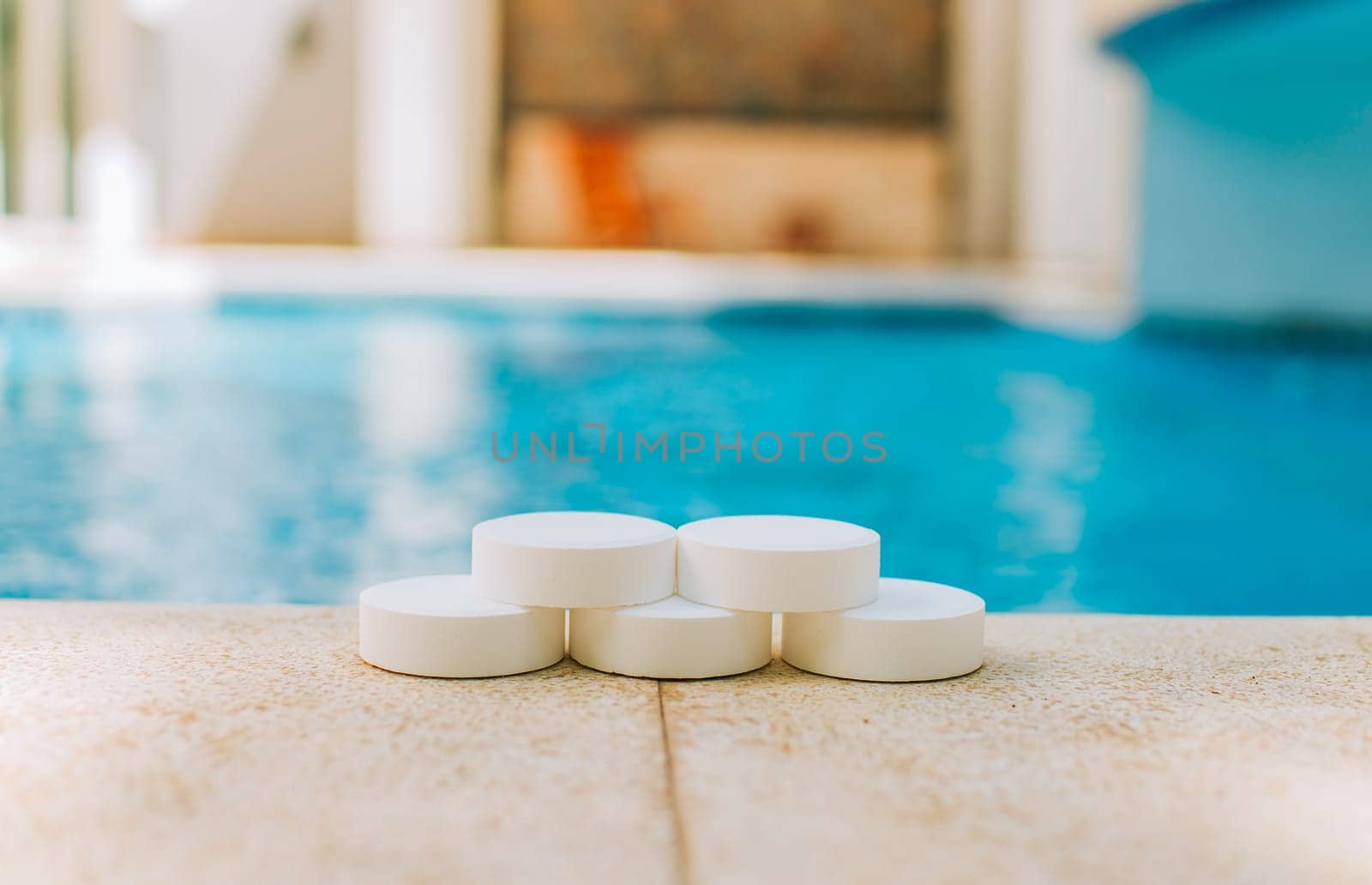 Chlorine tablets for disinfection and purification of swimming pools. Chlorine tablets with background of a crystal clear pool
