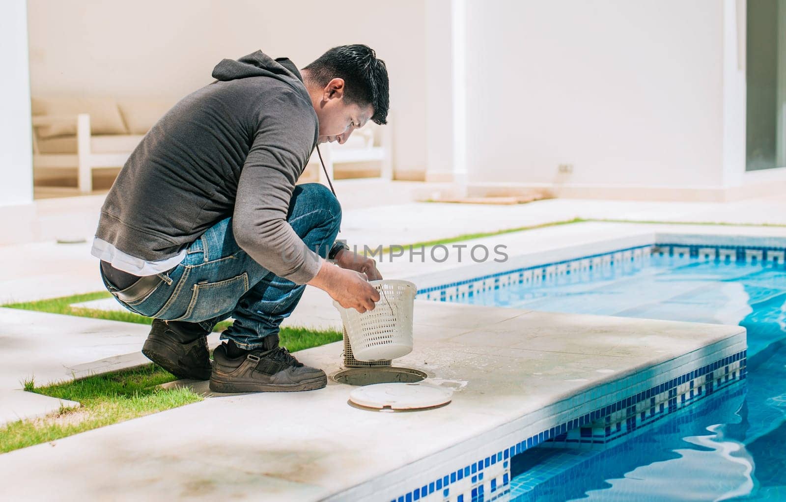 Worker removing trash from swimming pool filter basket. Man cleaning swimming pool garbage filter