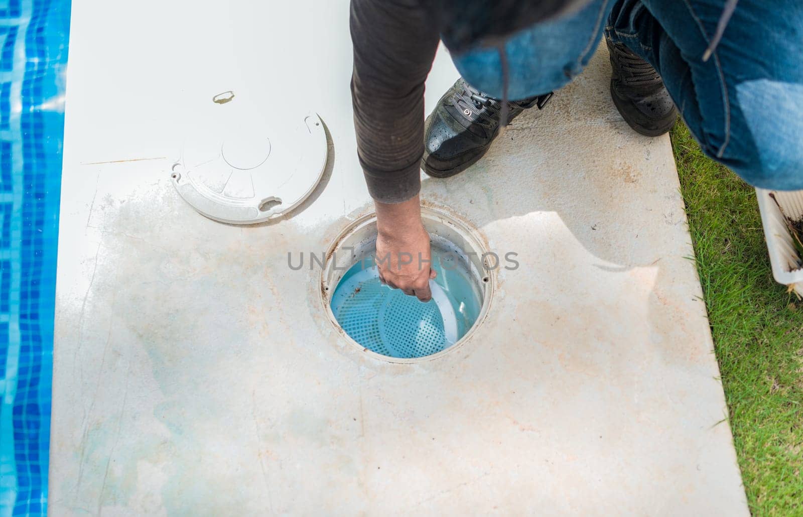 Person cleaning pool filter skimmer basket. Cleaning and maintenance of the swimming pool skimmer basket