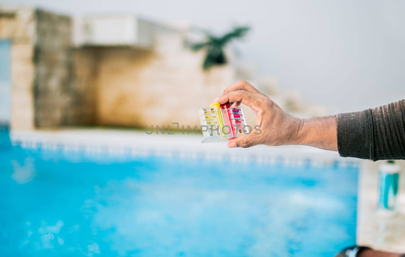 Hand showing tester kit to measure chlorine and ph in swimming pools. Person testing the PH of the swimming pool