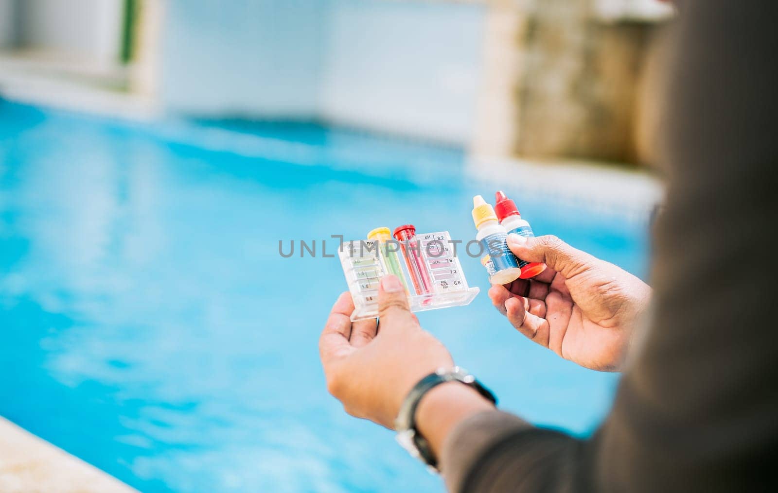 Person testing the PH of the swimming pool. Hand holding tester kit to measure chlorine and ph in swimming pools