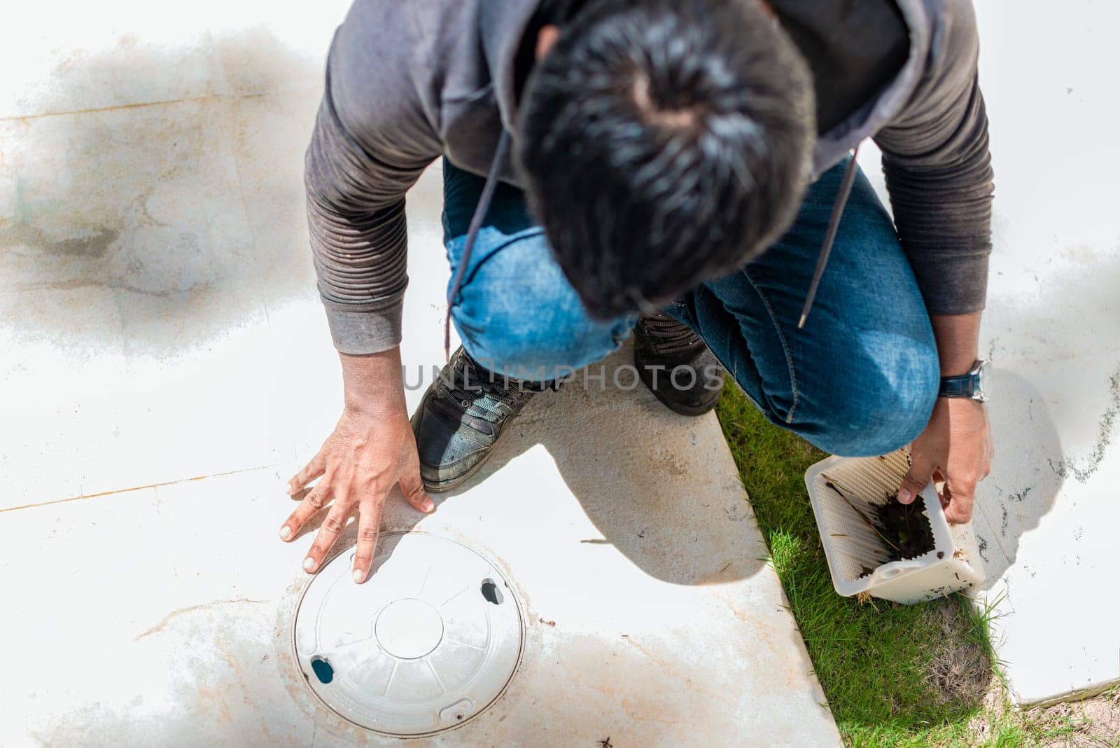 Worker changing swimming pool skimmer basket. Cleaning and maintenance of the swimming pool skimmer basket