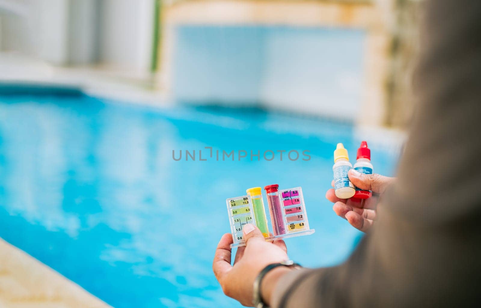 Hand holding tester kit to measure chlorine and ph in swimming pools. Person testing the PH of the swimming pool