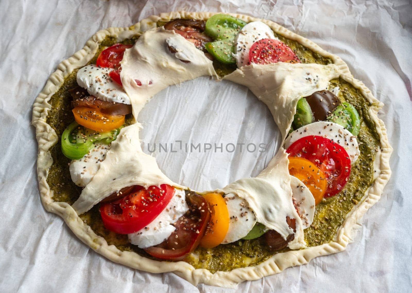 A pizza with a variety of vegetables including tomatoes, peppers, and cheese. The pizza is in the shape of a wreath