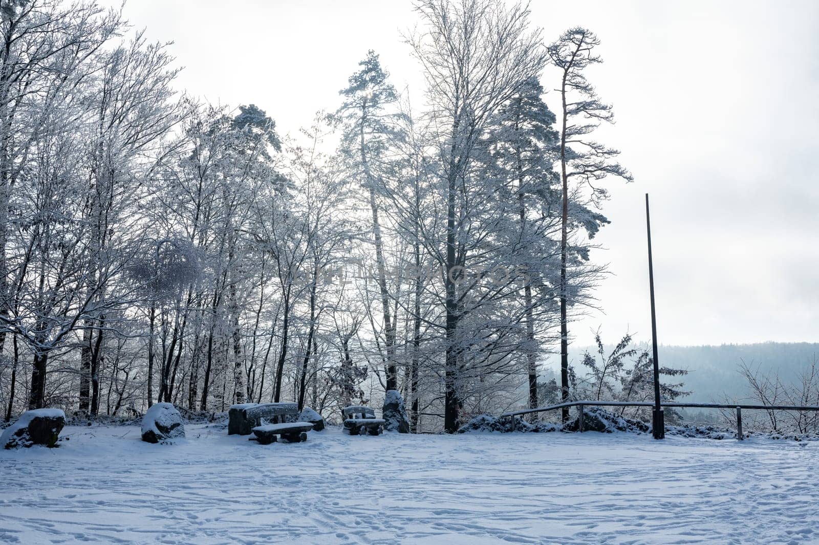 View of a landscape with snow , bench and trees