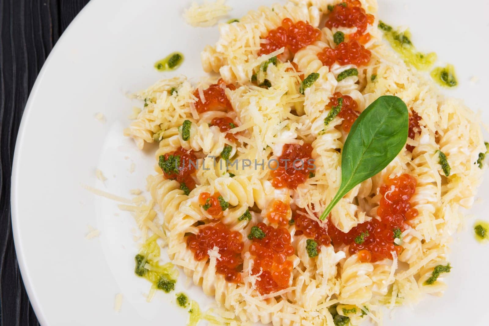 Pasta with parmesan cheese basil and red caviar. The concept of Italian cuisine.
