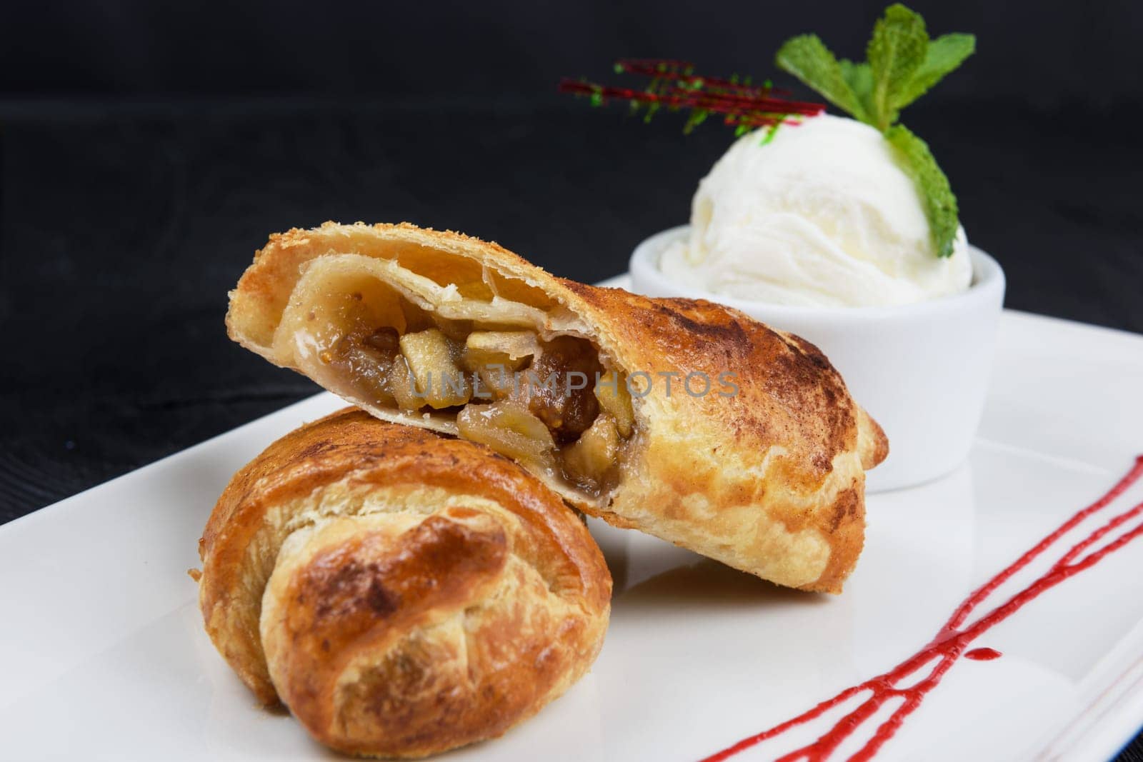 Apple strudel with vanilla ice cream decorated with caramel and berries sauce