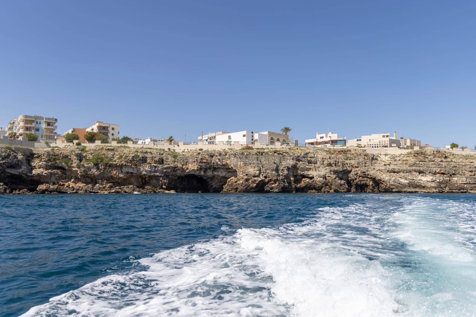 Polignano a Mare, Italy, Apulia - May 24, 2024: View from the water of picturesque coastline with cliffs and caves by Adriatic Sea. Boat cruise along the rocky coast is a great tourist attraction