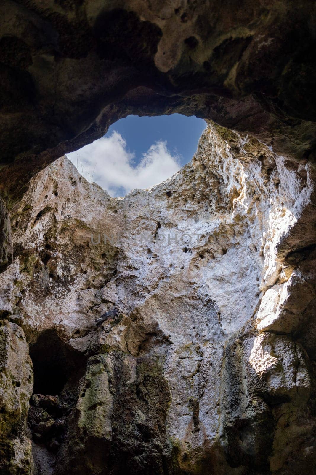 View of the sky from inside the grotto through an opening in the cliff, Polignano a Mare, Italy, Apulia. The city is famous for about 400 water caves visible only from the sea