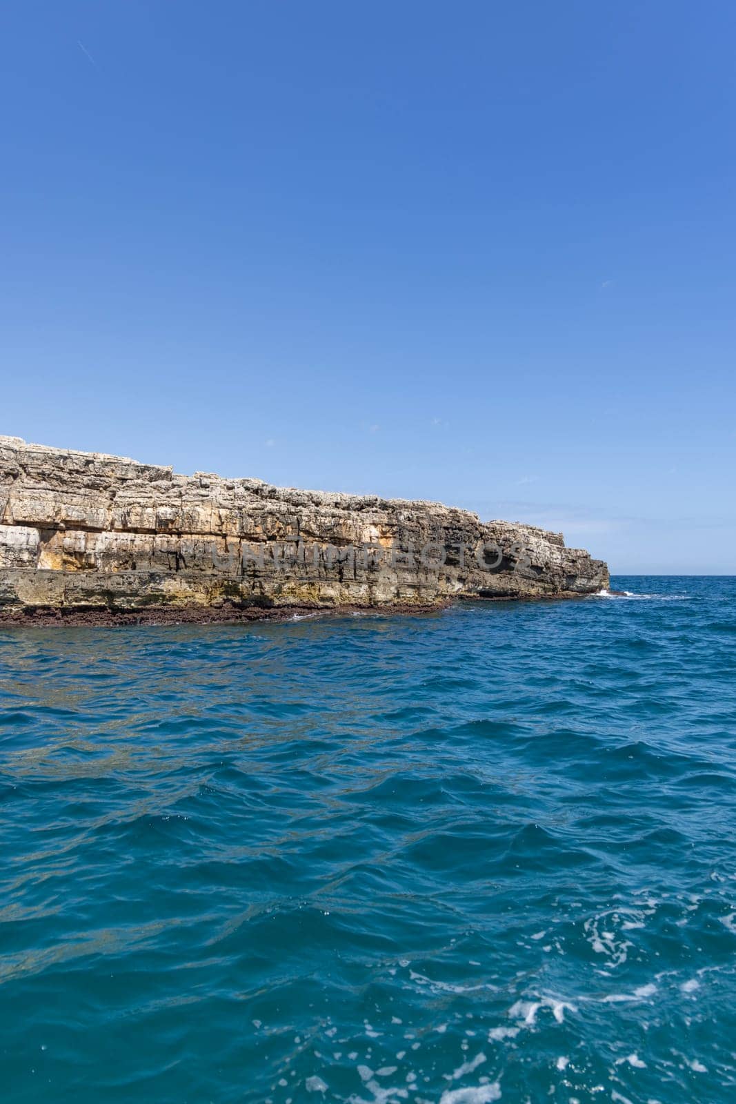 View from the water of picturesque coastline with cliffs and caves by Adriatic Sea, Polignano a Mare, Italy, Apulia. Boat cruise along the rocky coast is a great tourist attraction