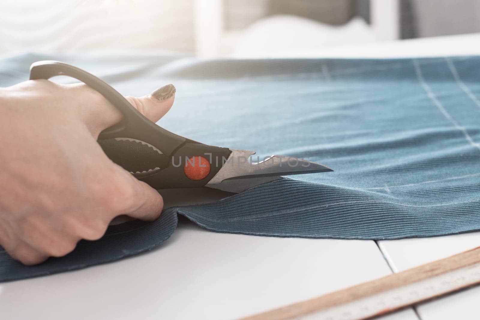 Woman dressmaker cutting fabric textile with scissors