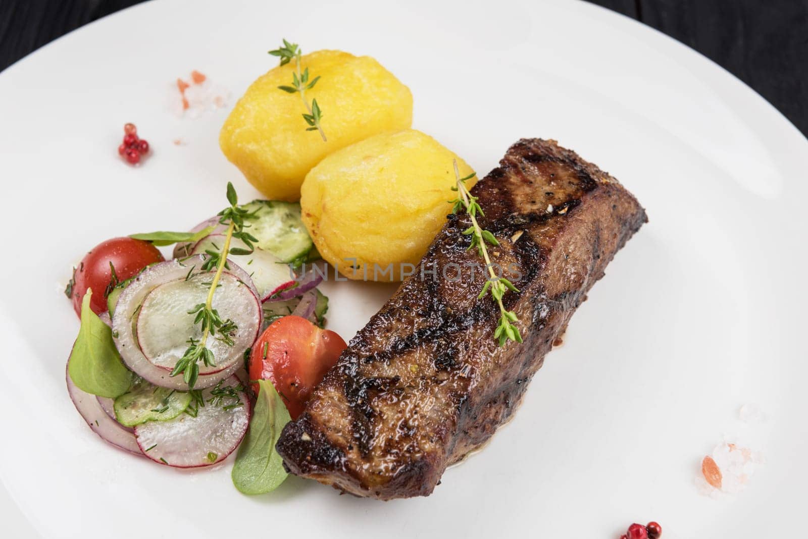 Grilled beef meat with potato and vegetables on white plate