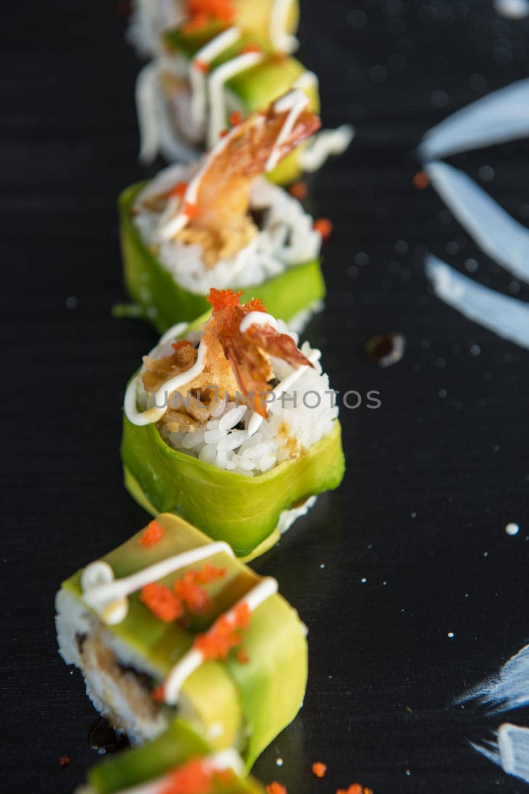 Various kinds of sushi served on wood black table.