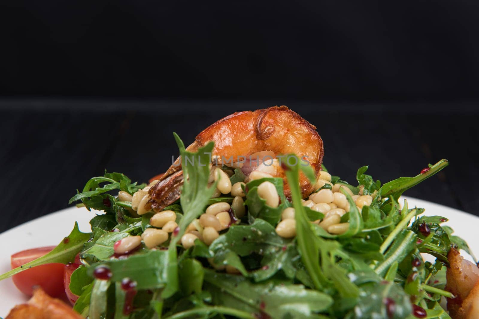 Green salad with shrimps: greens, arugula, tomato, pine nuts and sauce