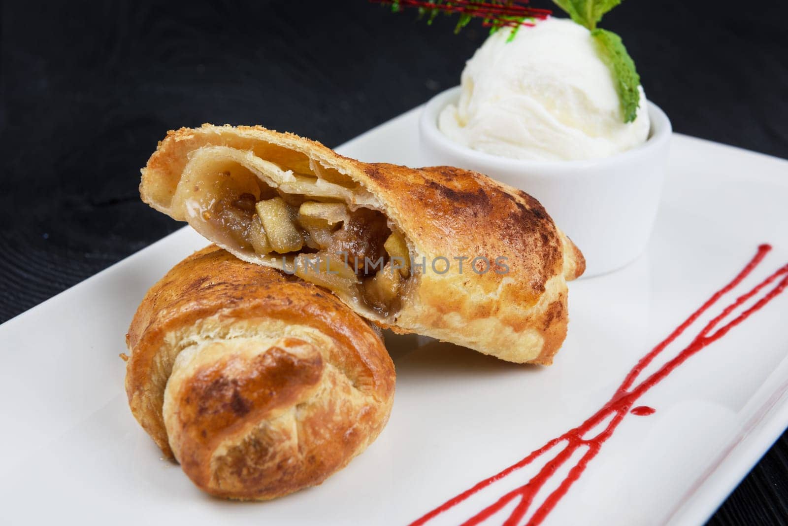 Apple strudel with vanilla ice cream decorated with caramel and berries sauce