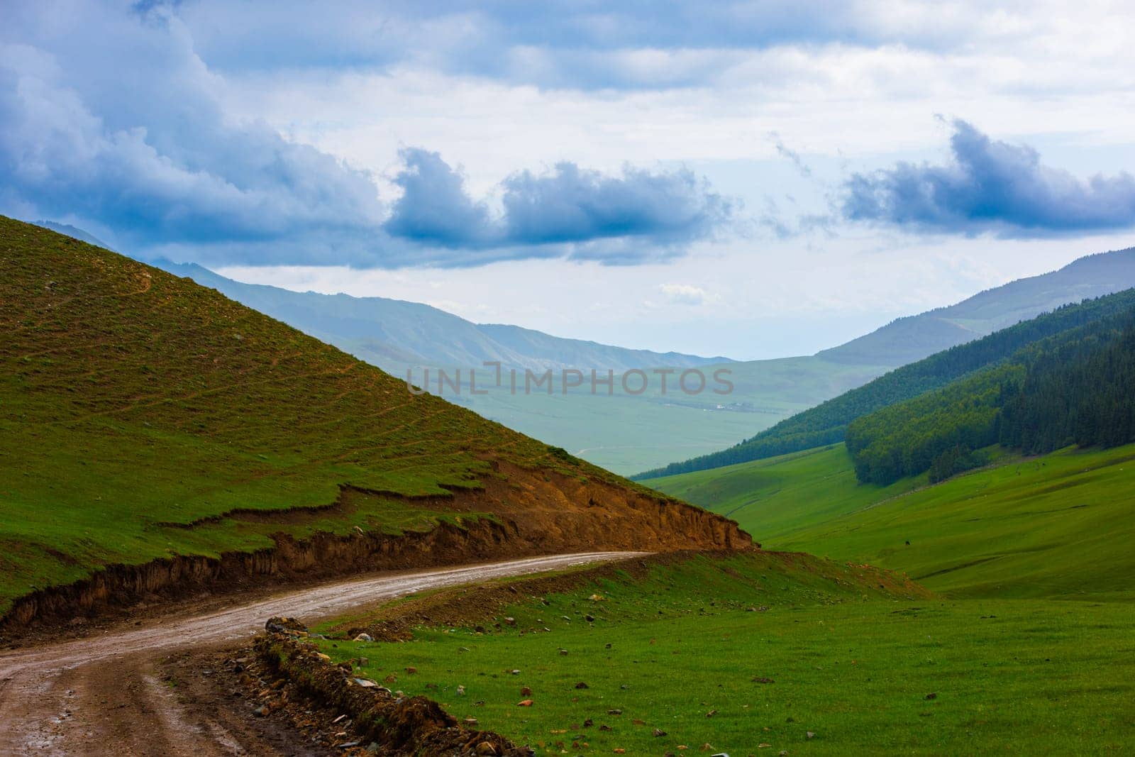 dirt road in the mountain hills at rainy summer day in Kyrgyzstan