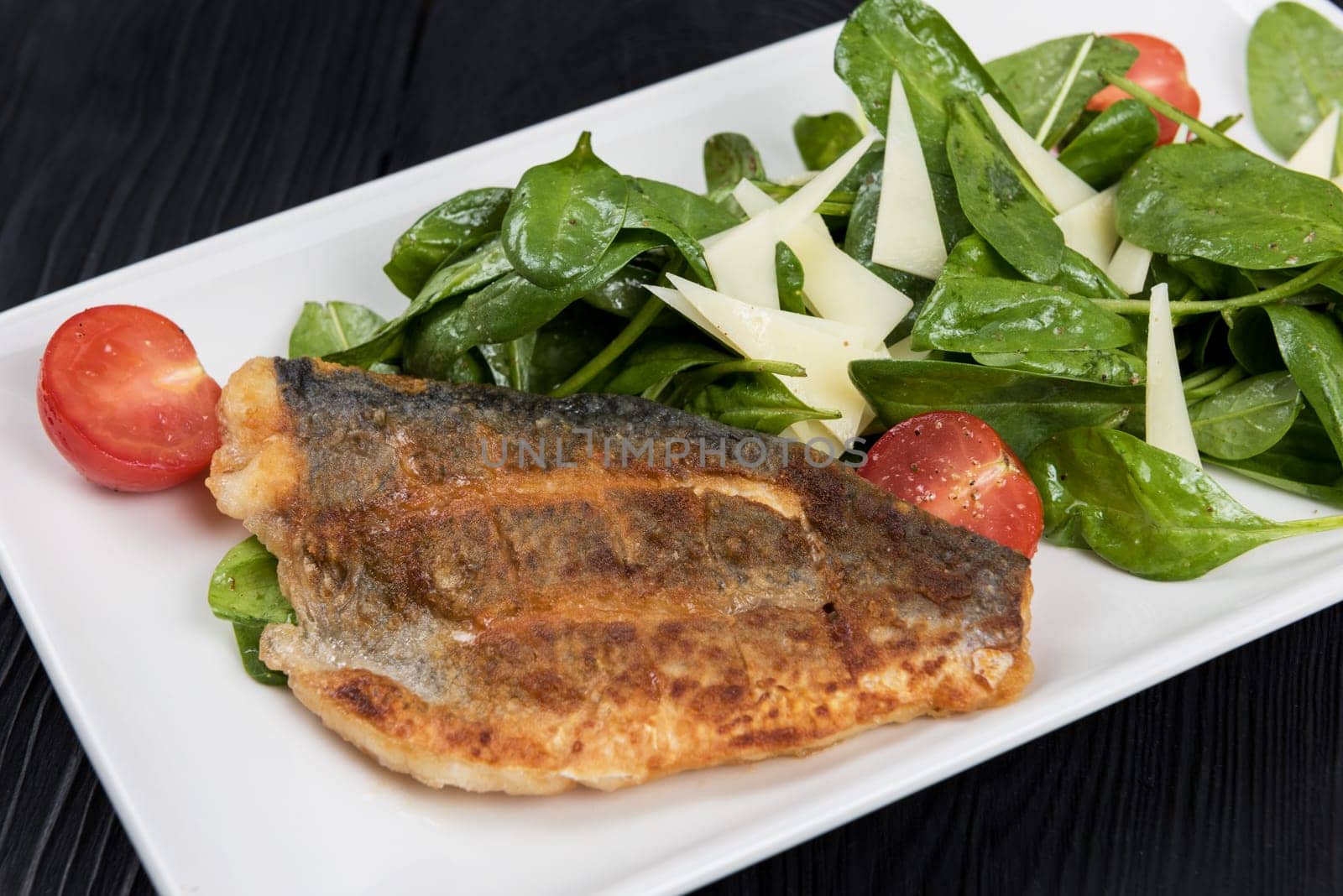 Grilled Dorado fish fillet with spinach, tomato and cheese