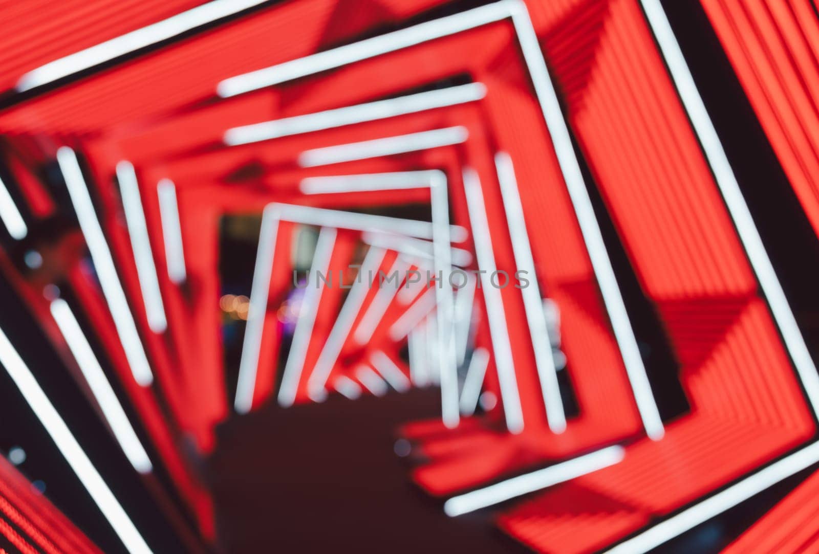 Futuristic neon tunnel with geometric abstract blur background . Vibrant red backdrop contrasts with white LED lines forming angular shapes.