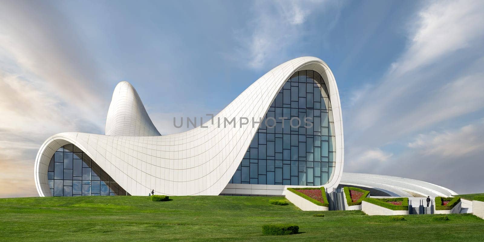 The iconic Heydar Aliyev Centre in Baku, Azerbaijan, showcases modern architecture with its fluid, wave-like design against a clear sky. Building designed by architect Zaha Hadid