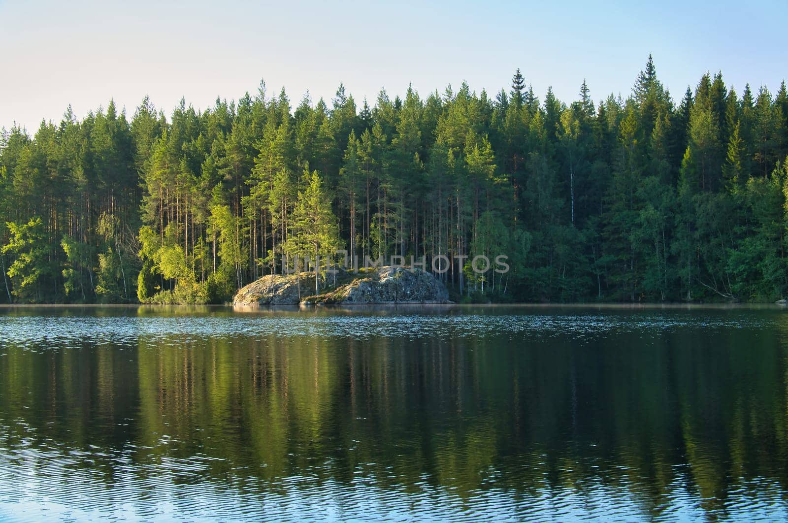 Lake in sweden with blue sky and white clouds in front of blue water. Trees on the shore. Nature from Scandinavia