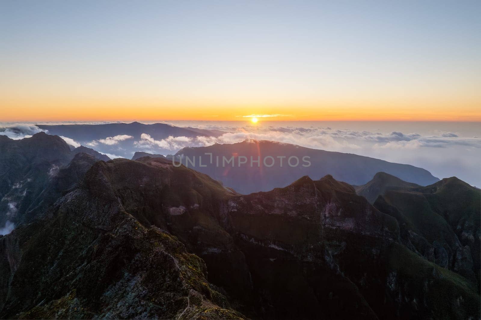 Aerial drone view of mountains over clouds near Pico Ruivo on sunset. Madeira island, Portugal