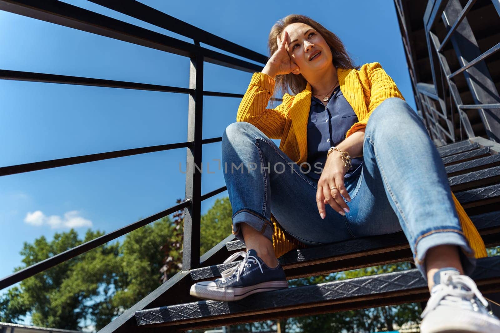 thoughtful woman sitting alone on outdoor stairs.
