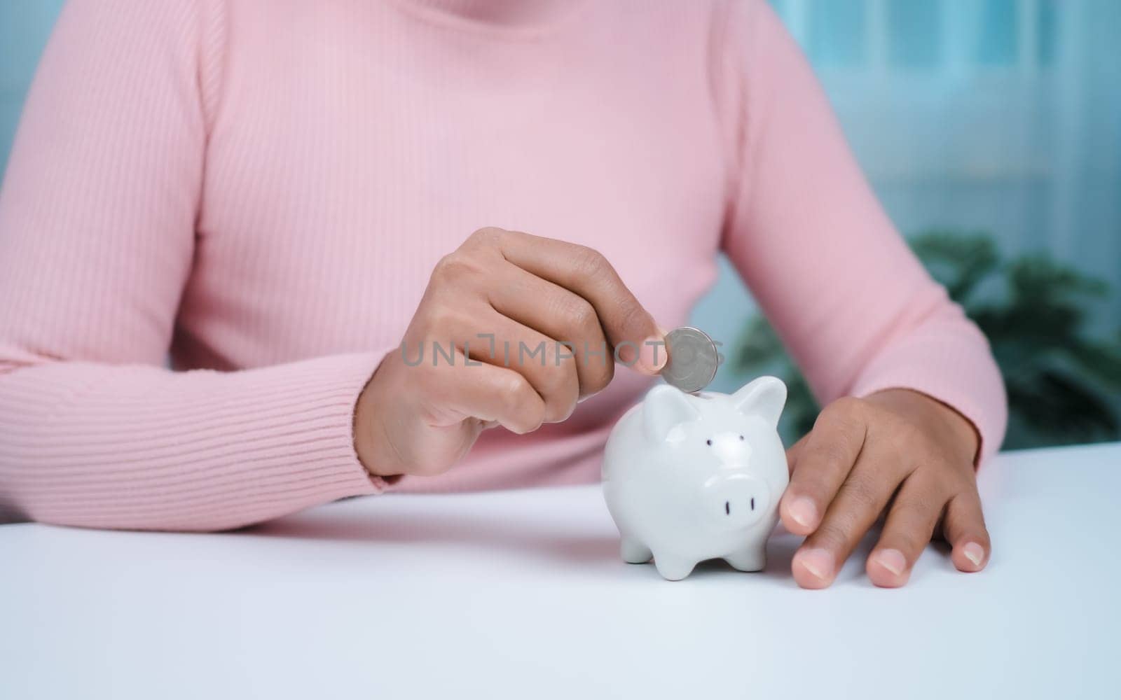 Close-Up Woman put coins in the piggy bank for saving money and financial concept, Business Banking and Financial Concept, Saving money for retirement funds and insurance concept.