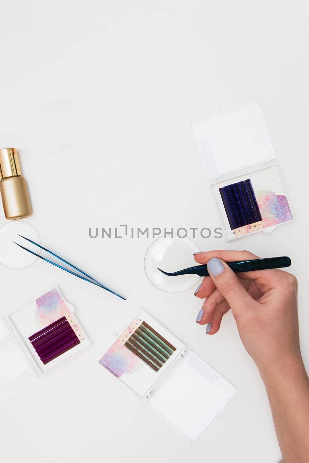 Tools for eyelash extension procedure. Hand with tweezers with artificial black lashes on gray background. Beauty concept