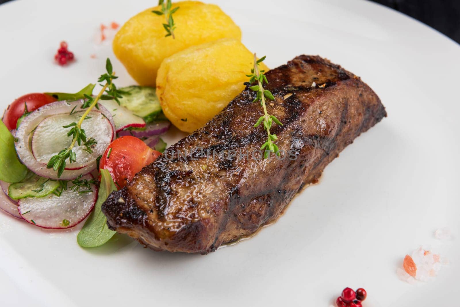 Grilled beef meat with potato and vegetables on white plate