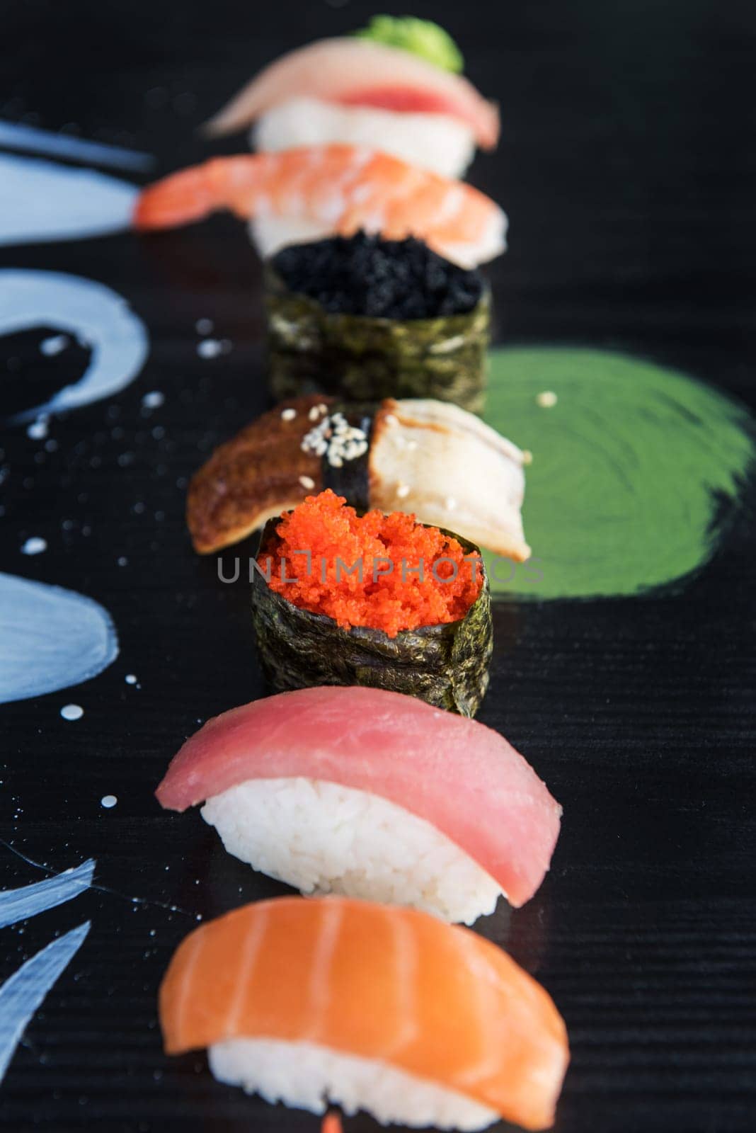 Various kinds of sushi served on wood black table.
