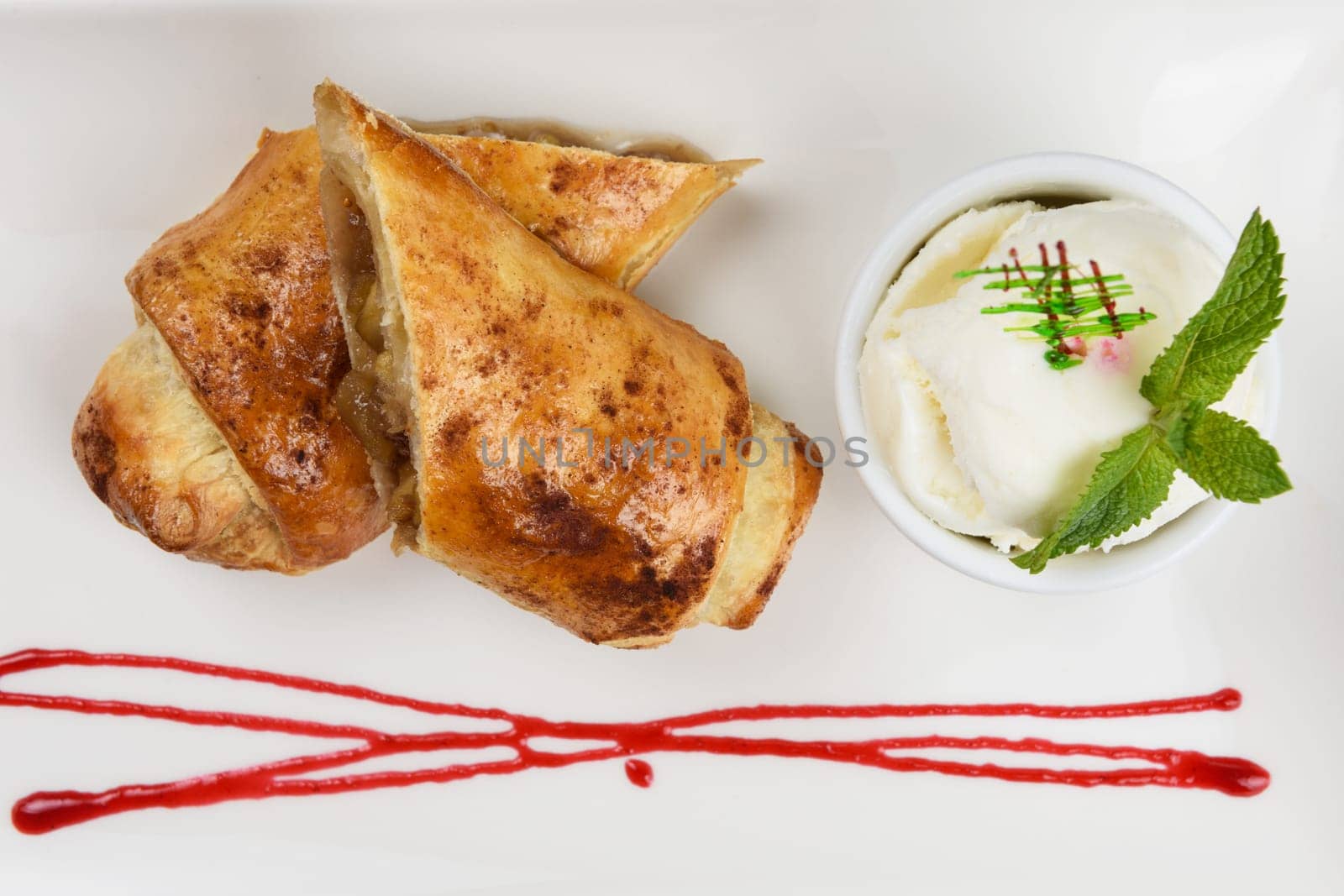 Apple strudel with vanilla ice cream decorated with caramel and berries sauce