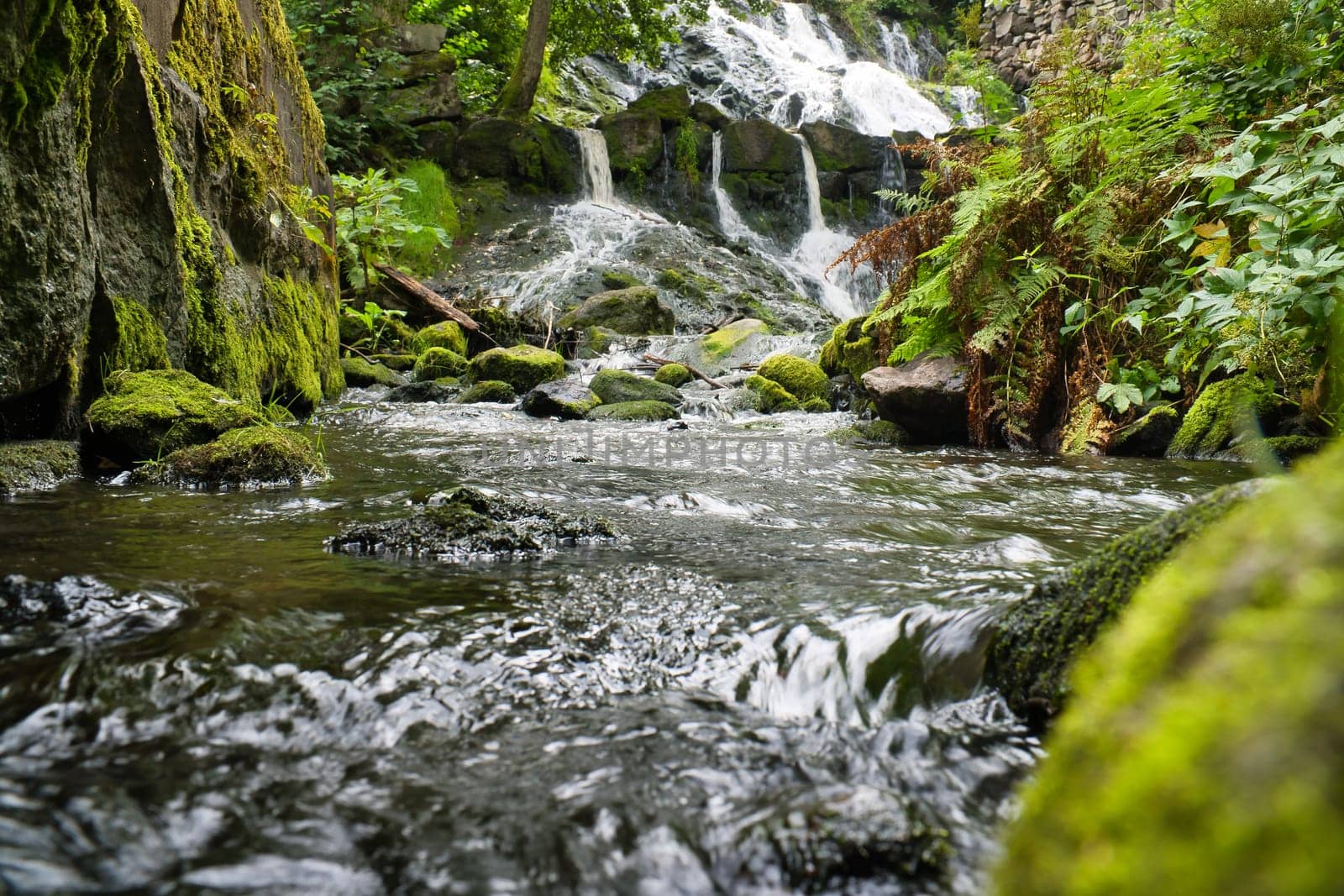 Small river in Sweden with several small waterfalls. Moss-covered stones. Forest on the shore. Scandinavian nature