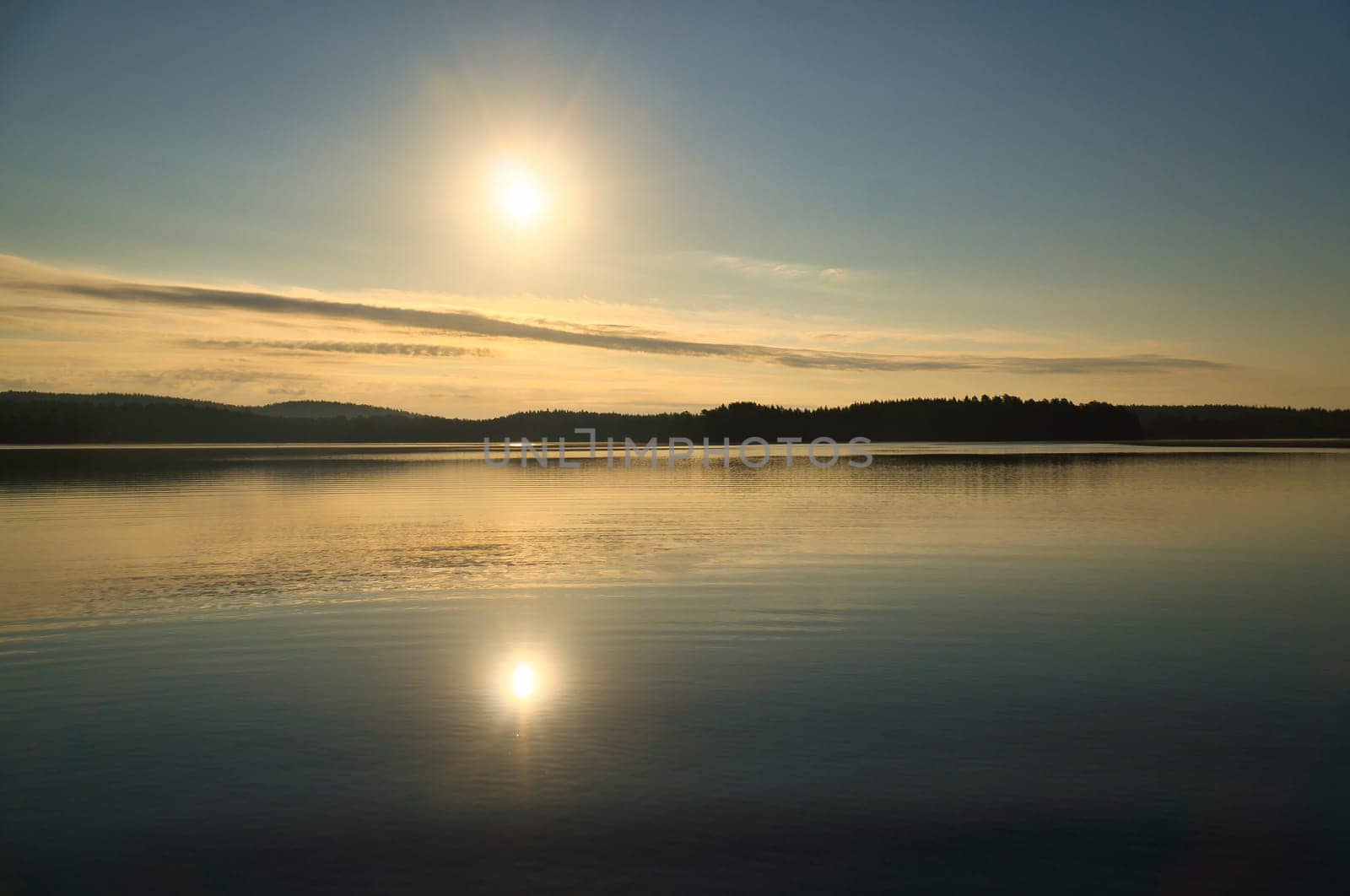 Sunrise over a Swedish lake with mirror-smooth water in front of trees on the shore. Nature shot from Scandinavia