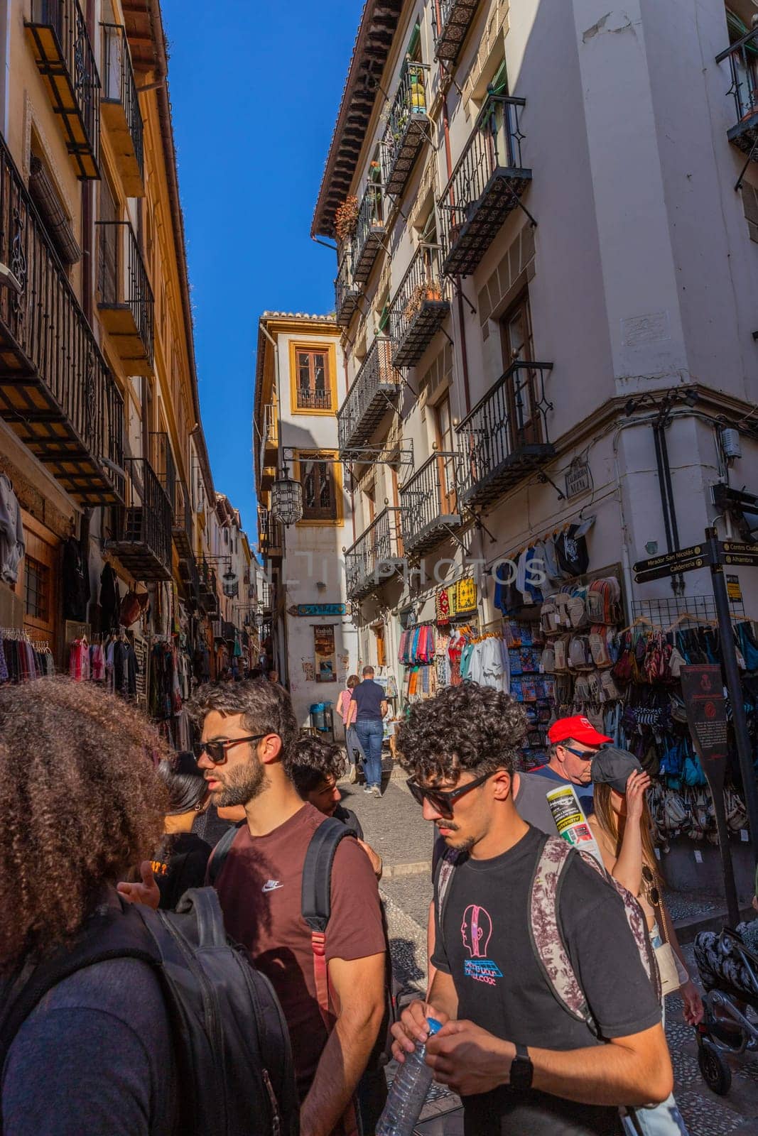 Granada, Spain: April 15, 2024: People walking in a charming narrow shopping street in the historic city centre. Andalusia, Spain