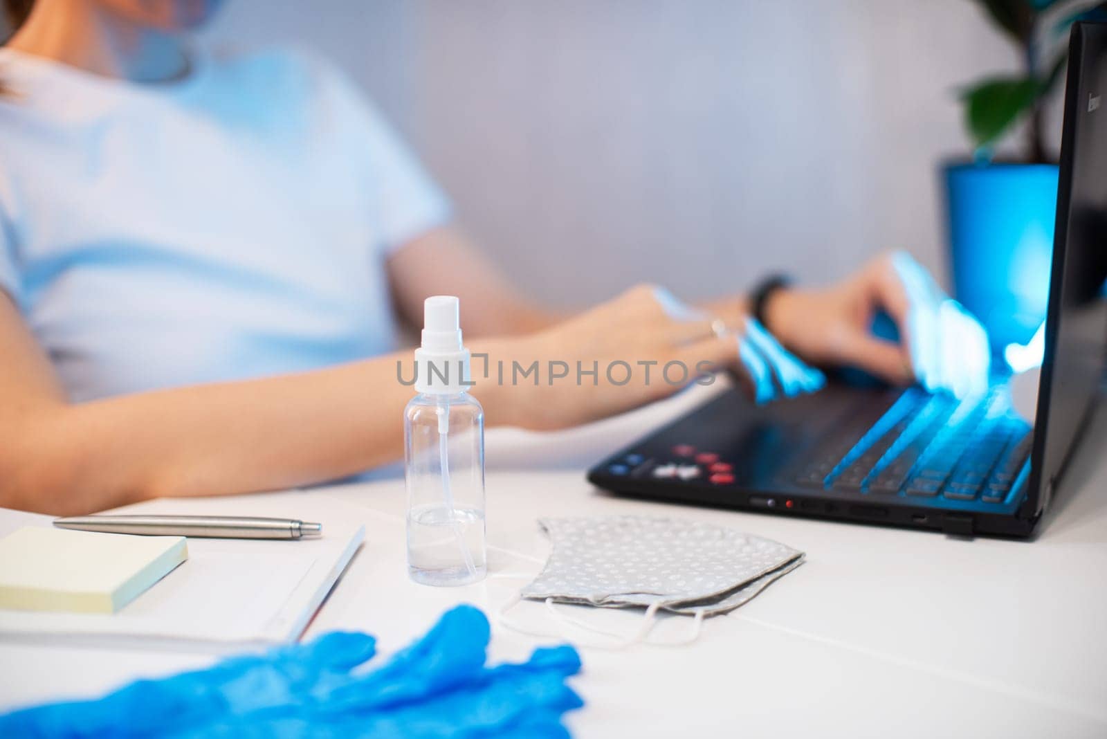 Coronavirus concept. Woman in quarantine for coronavirus covid-19 working from home. Protective mask and Sanitizer spray on the working place
