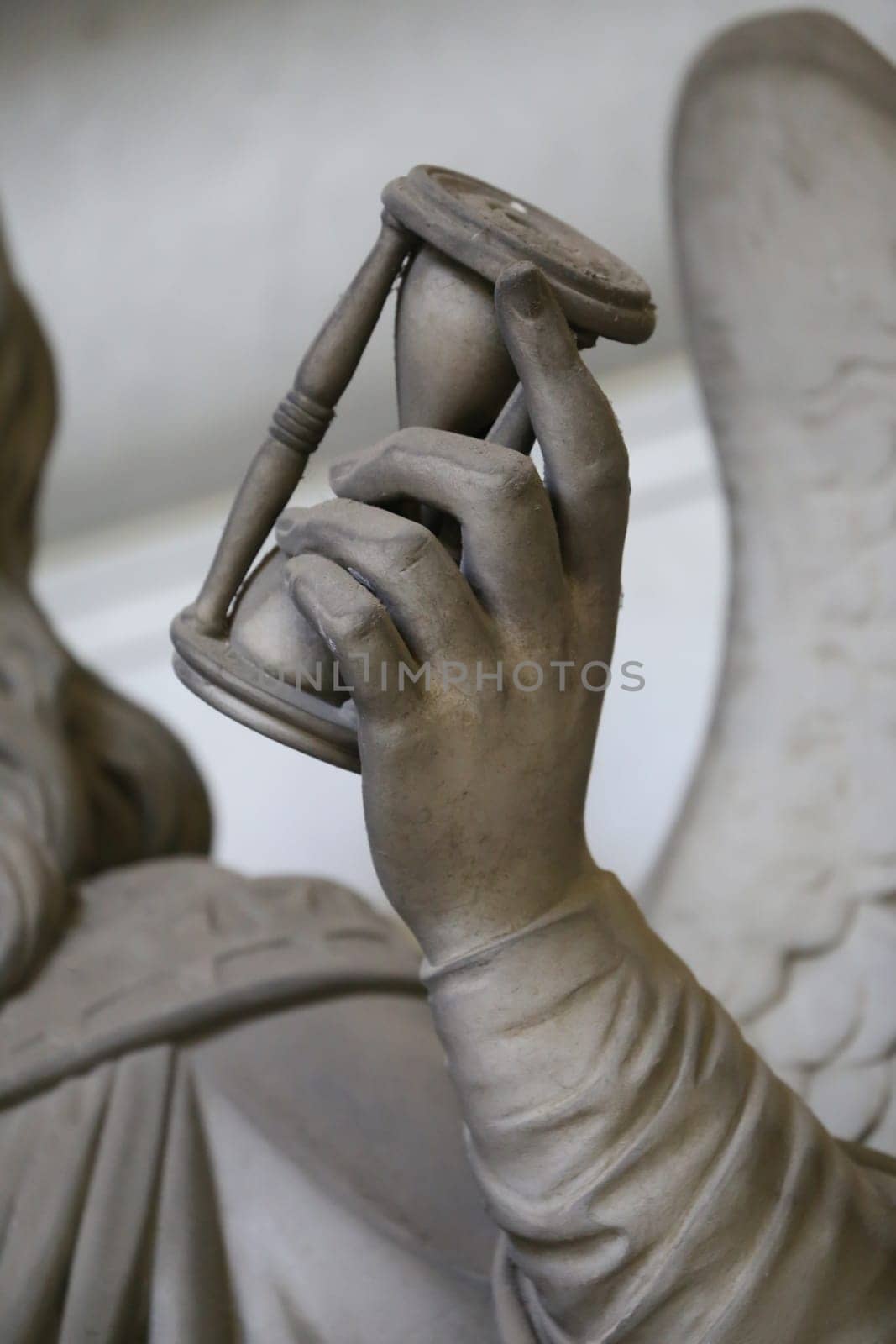 Antique statue holding a sandglass. Concept of time passing, countdown, retro hourglass
