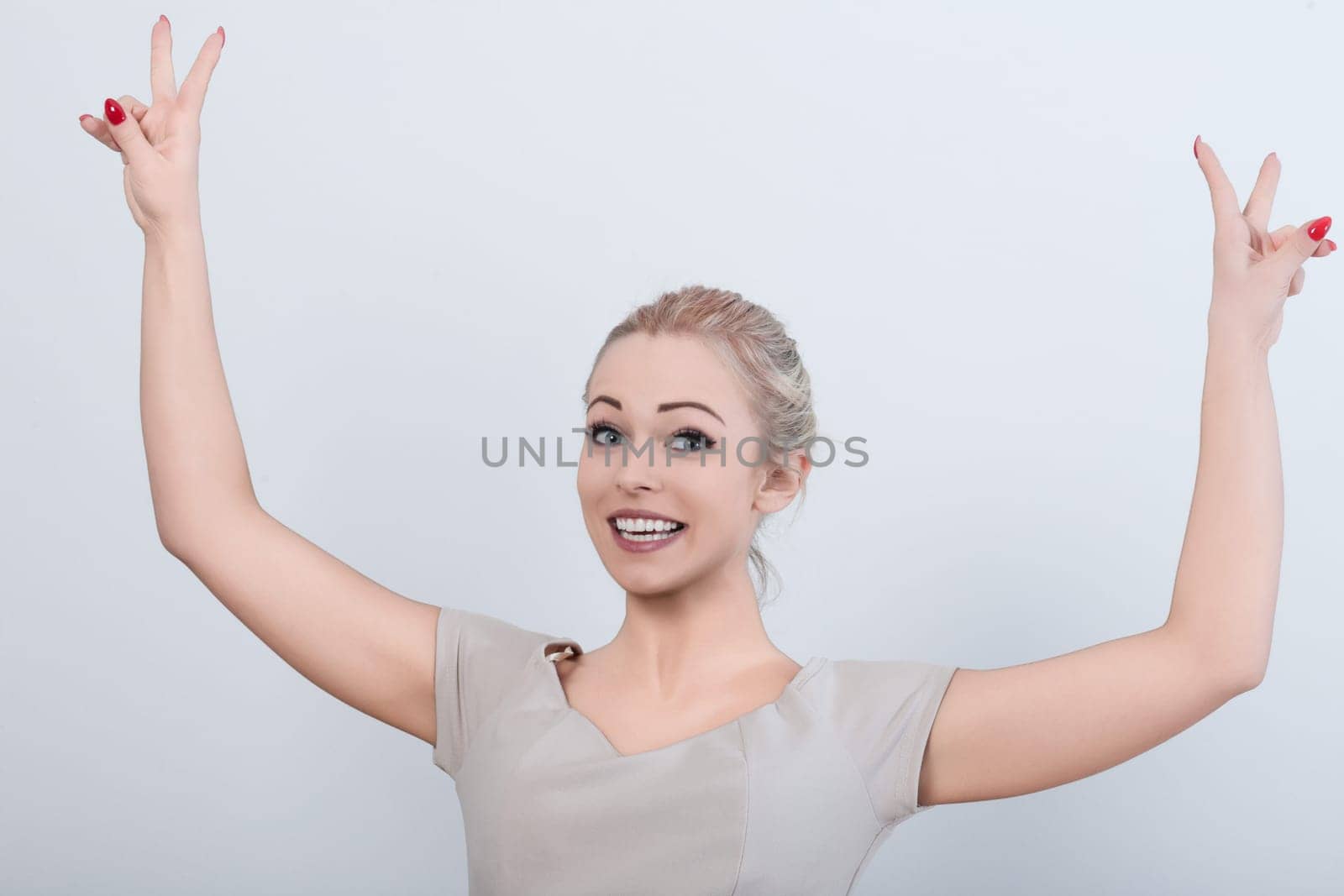 Joyful businesswoman celebrates success in her office, flashing a victory sign with a beaming smile
